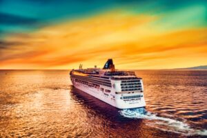 A cruise ship on the sea with a sunset