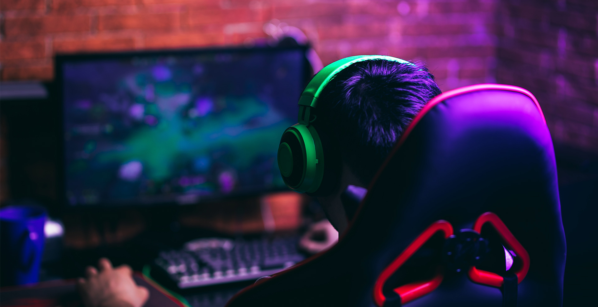 A young man is in front of a computer and plays video games