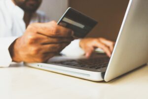 A man in front of a computer holds a bank card in his hand