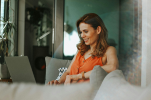 A woman uses a laptop on a sofa